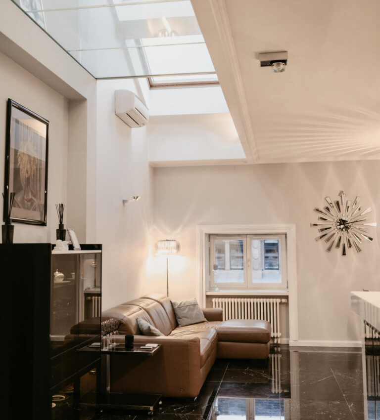 Nowoczesny salon z elegancką kanapą, dekoracyjnym zegarem i oknem dachowym.